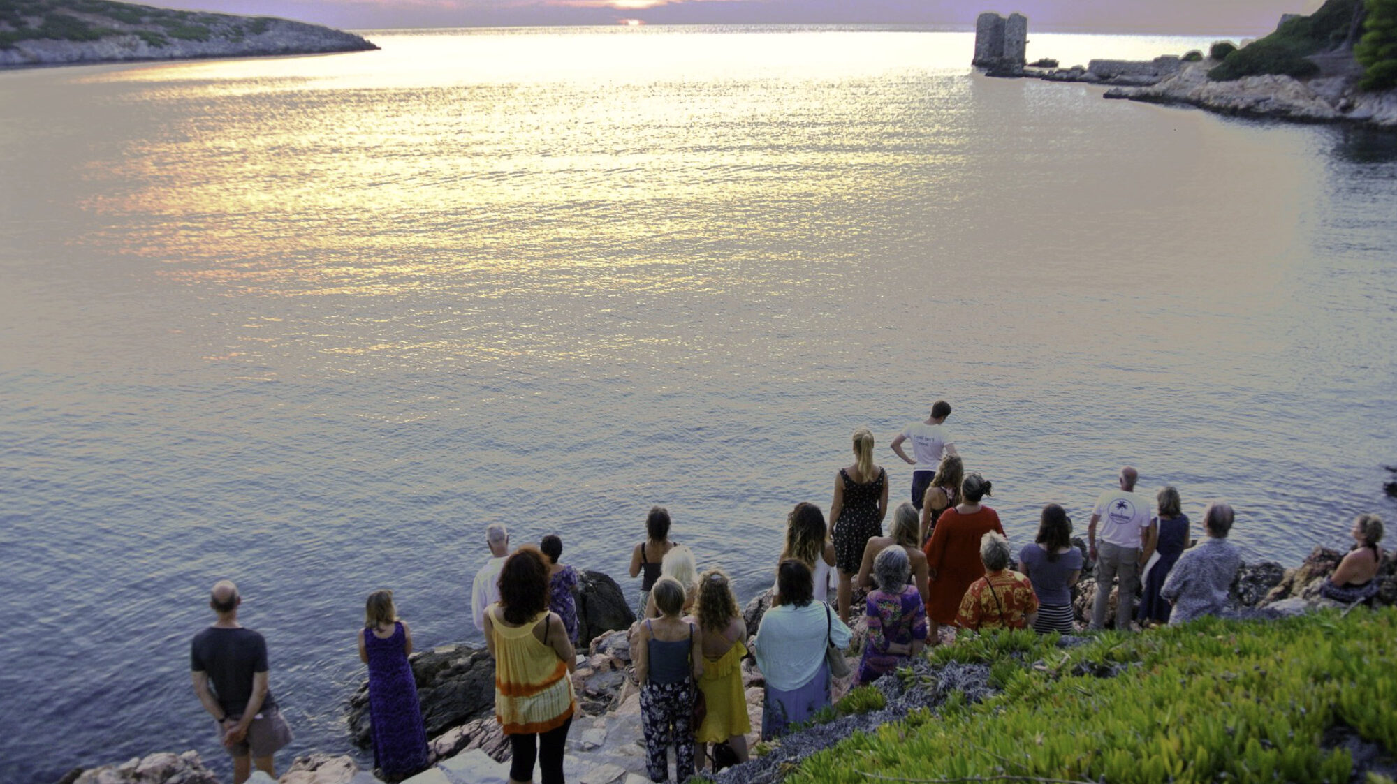 Meditation group watching towards the ocean in sunset scene